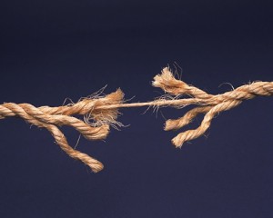 Frayed rope about to break isolated on blue background